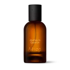 Bernsteinfarbene Flasche des Aesop Journey to Ouranon Eau de Parfum aus Glas mit schwarzem Verschluss vor weißem Hintergrund.
