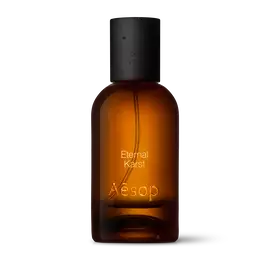 Bernsteinfarbene Flasche des Aesop Eternal Karst Eau de Parfum aus Glas mit schwarzem Verschluss vor weißem Hintergrund.