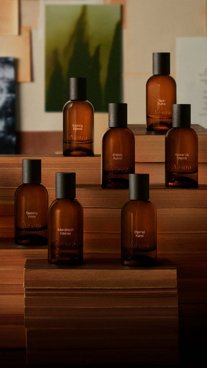 Aesop Parfumflaschen aus Bernsteinglas auf gestapelten Buchern.