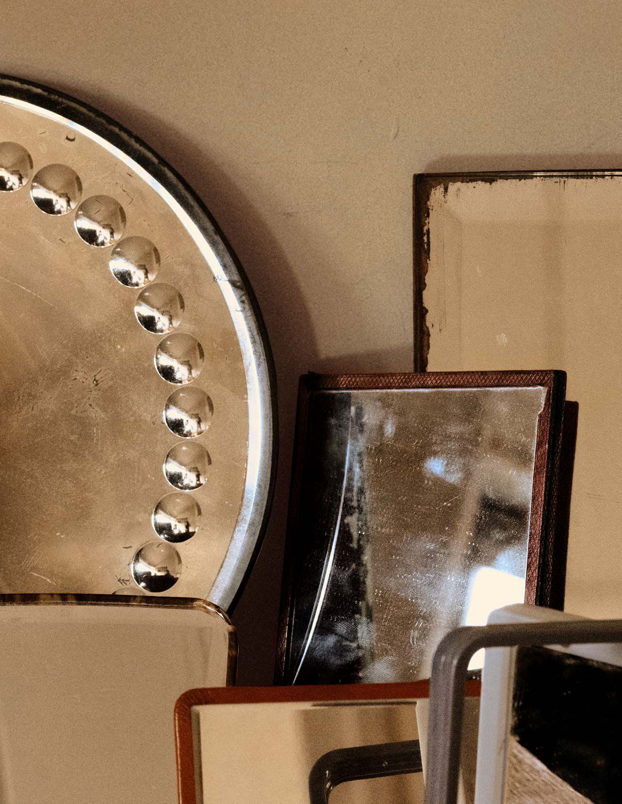 Ubereinandergeschichtete Objekte aus Metall und Stein in Bronze-, Beige- und Dunkelbrauntonen, als sich uberlagernde geometrische Formen vor einer neutralen Wand arrangiert.